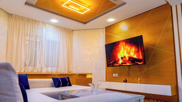 Een moderne woonkamer met een bank, televisie en open haard.