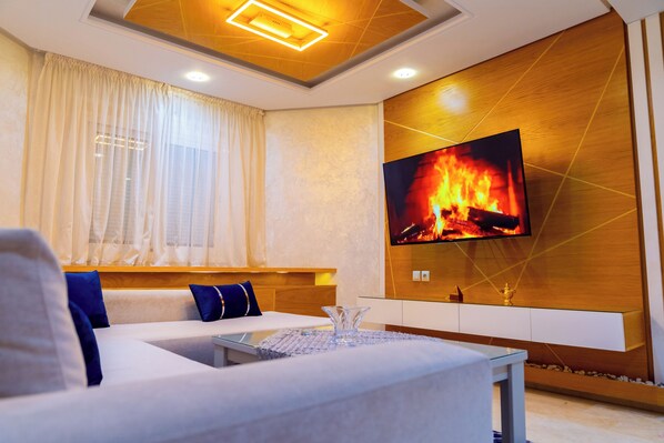 Ein modernes Wohnzimmer mit Sofa, Fernseher und Kamin.