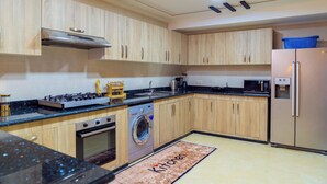 Een moderne keuken met houten kastjes, een RVS fornuis, een ingebouwde wasmachine en een koelkast.
