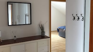 A modern room with a wooden dresser, a mirror, a small plant, and a coat rack.