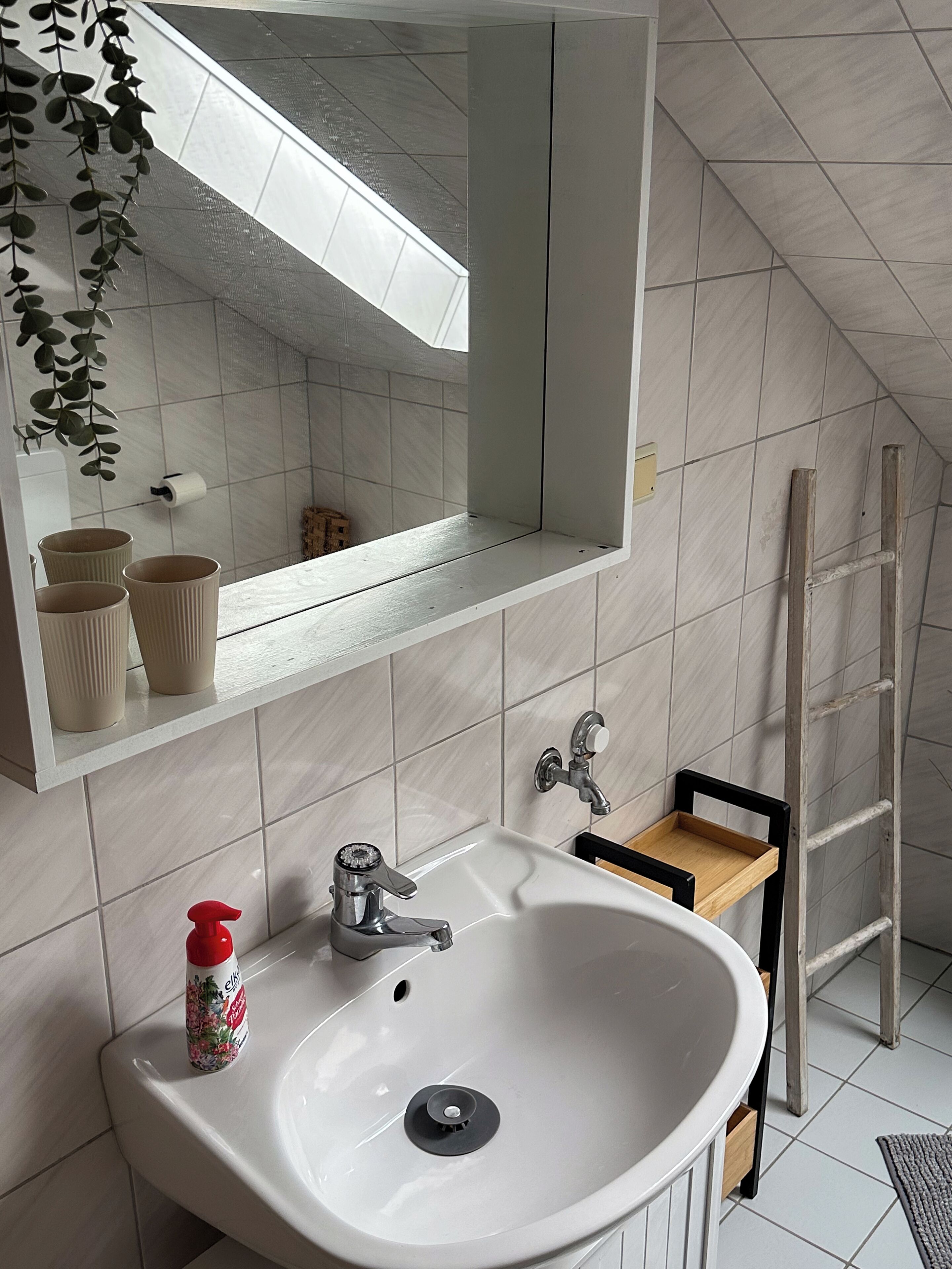 A bathroom with a white sink, two faucets, a mirror, and a towel rack.