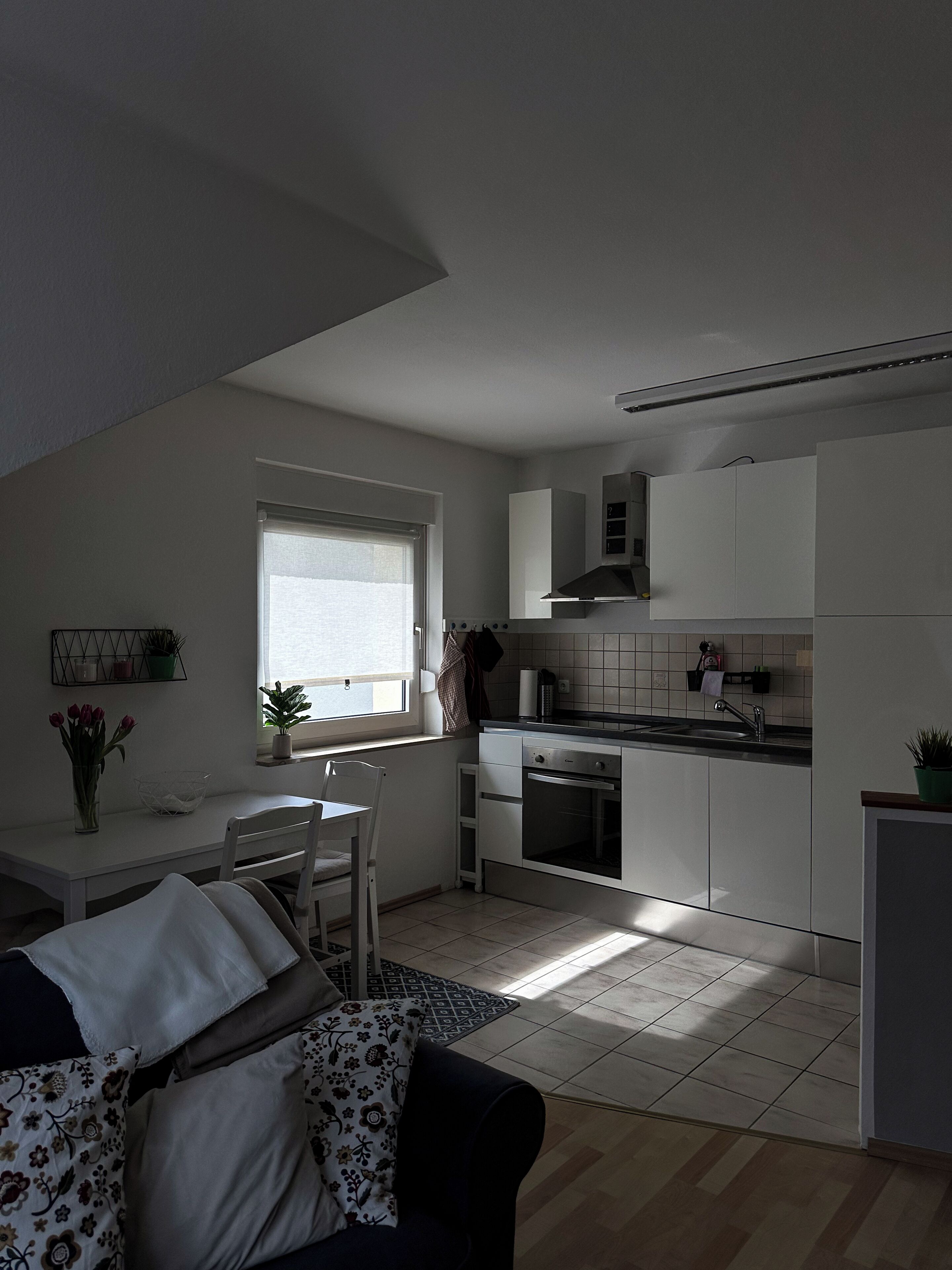 A compact kitchen with a dining area, a window, and a small refrigerator.