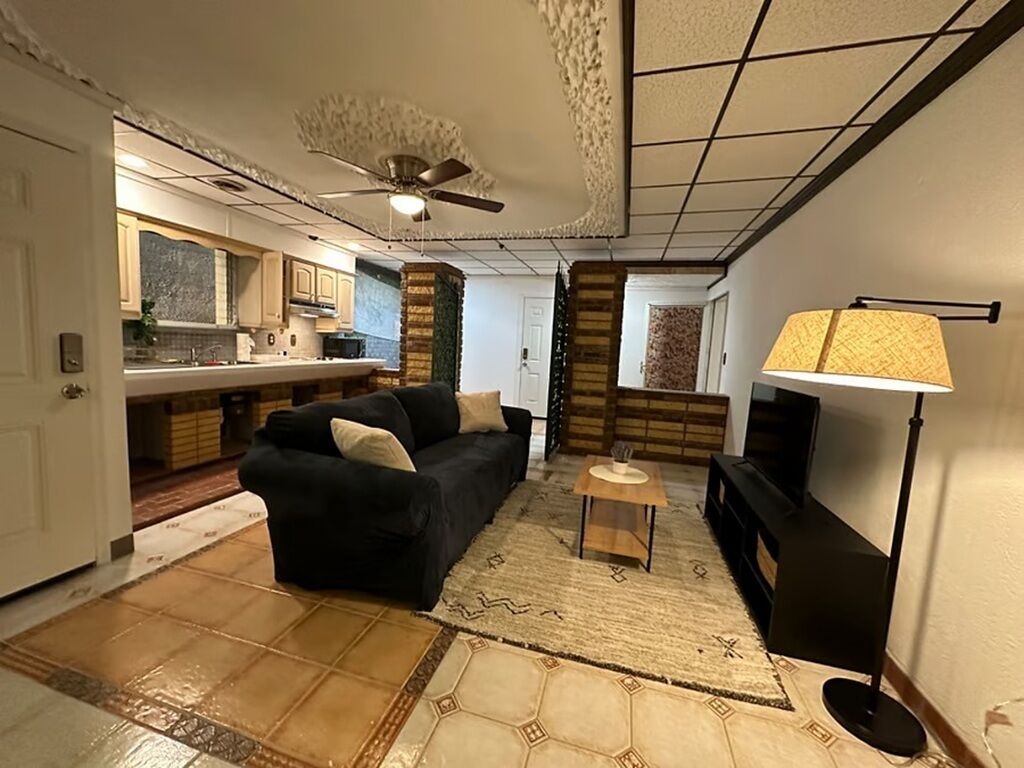 A living room with a sofa, a coffee table, a TV, and a lamp.