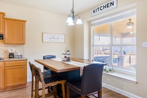 Une cuisine avec des meubles en bois, une table à manger avec des chaises, une fenêtre donnant sur un beau paysage et un panneau indiquant qu'il s'agit de la cuisine.