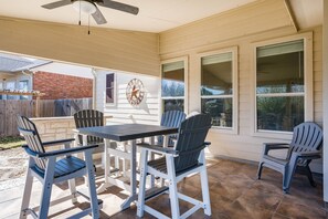 Une terrasse avec une table et des chaises, un ventilateur de plafond et une horloge au mur.