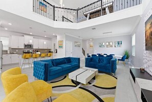 Amplia sala de estar con techo alto, una cocina al fondo y una escalera que sube a un nivel superior.