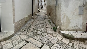 A narrow cobblestone street flanked by white buildings with balconies and a sign reading 'N. FRA LODGE'. - Casa Corteseapulia, ideale per due persone, immersa nella quiete più totale. (Putignano)