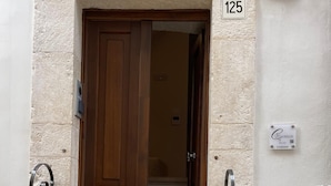 A wooden door with a number '125' above it, a small plaque with text, and a metal handrail on the right. - Casa Corteseapulia, ideale per due persone, immersa nella quiete più totale. (Putignano)