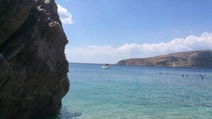 Eine Küstenlandschaft mit klarem Wasser, einem Boot und felsigen Klippen.