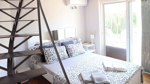 Ein Schlafzimmer mit Bett, Treppe, Fenster und Tür.