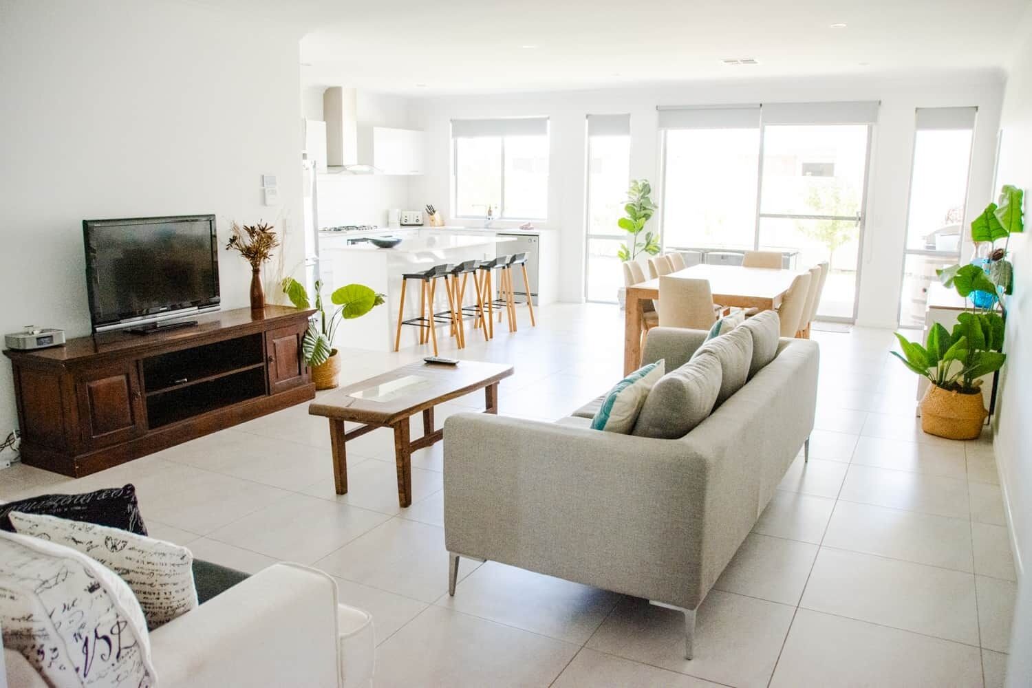 En moderne stue med sofa, sofabord, fjernsyn og spiseplads.