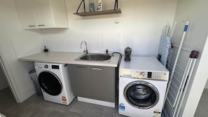 Un lavadero pequeño con lavadora, secadora y lavabo.
