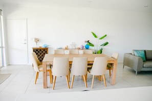 Ein Esszimmer mit Holztisch und -stühlen, einer Pflanze und einem Sofa.