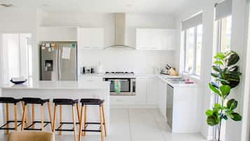 A modern kitchen with white cabinetry, a central island with bar stools, a built-in oven, and a large window.