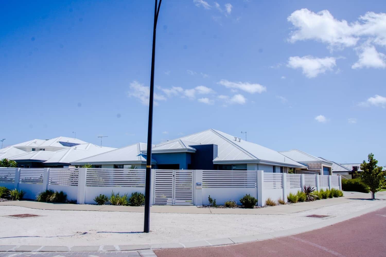 A modern building with a flat roof, a gated entrance, and a clear sky.