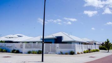 A modern building with a flat roof, a gated entrance, and a clear sky.