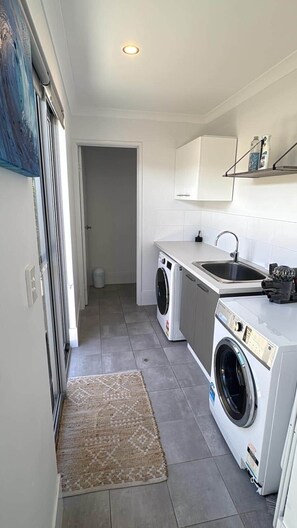 Una cocina compacta con lavadora, un lavamanos y un mueble pequeño.