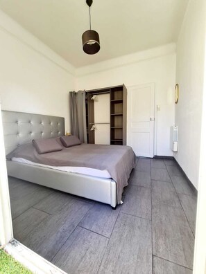 Una camera da letto con un letto, un armadio, una lampada a sospensione e una porta.