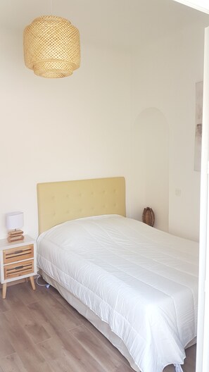 Una camera da letto con un letto, un comodino, una lampada e un lampadario.
