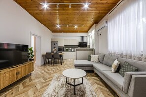 A modern living room with a TV, sofa, and dining area. - Konak Olive Guesthouse | Heart of Vlora by PikHost (Vlorë)