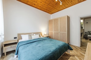 Een slaapkamer met een bed, nachtkastjes, een kledingkast en een houten plafond.