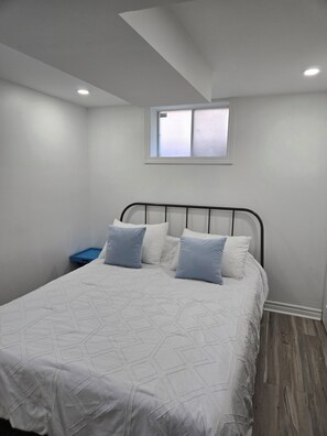 Una camera da letto con un letto, una finestra e un comodino blu.