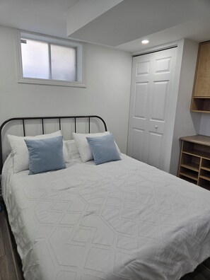 Una camera da letto con un letto, una finestra, una porta e una mensola in legno.