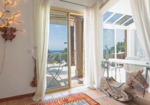 Ein Zimmer mit einer Glasschiebetür, die auf eine Außenpatio führt, einer dekorativen Pferdeskulptur und einem Tisch mit Stühlen.
