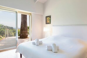Ein Schlafzimmer mit einem großen Bett, einer Schiebetür zum Balkon und einem gerahmten Bild an der Wand.