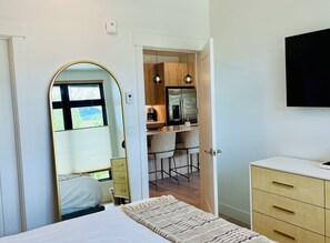A bedroom with a bed, a bedside table, a dresser, and a TV mounted on the wall.