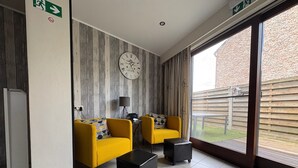 Una habitación moderna con dos sillones amarillos, una mesita de centro negra y un reloj en la pared.