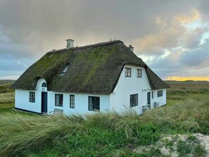 A white house with a thatched roof, surrounded by grass and dunes. - Architect's house from 1915 near Henne Strand (Nr. Nebel)