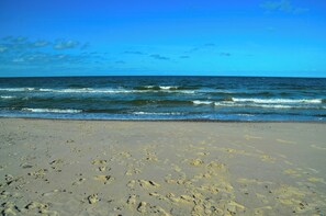 Ein Strand mit Fußabdrücken im Sand und ankommenden Wellen.