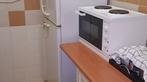 A compact kitchen with a refrigerator, microwave, and stove, featuring a tiled backsplash and a wooden countertop. - Room-boutique Self Catering Guesthouse 4 (Johannesburg)
