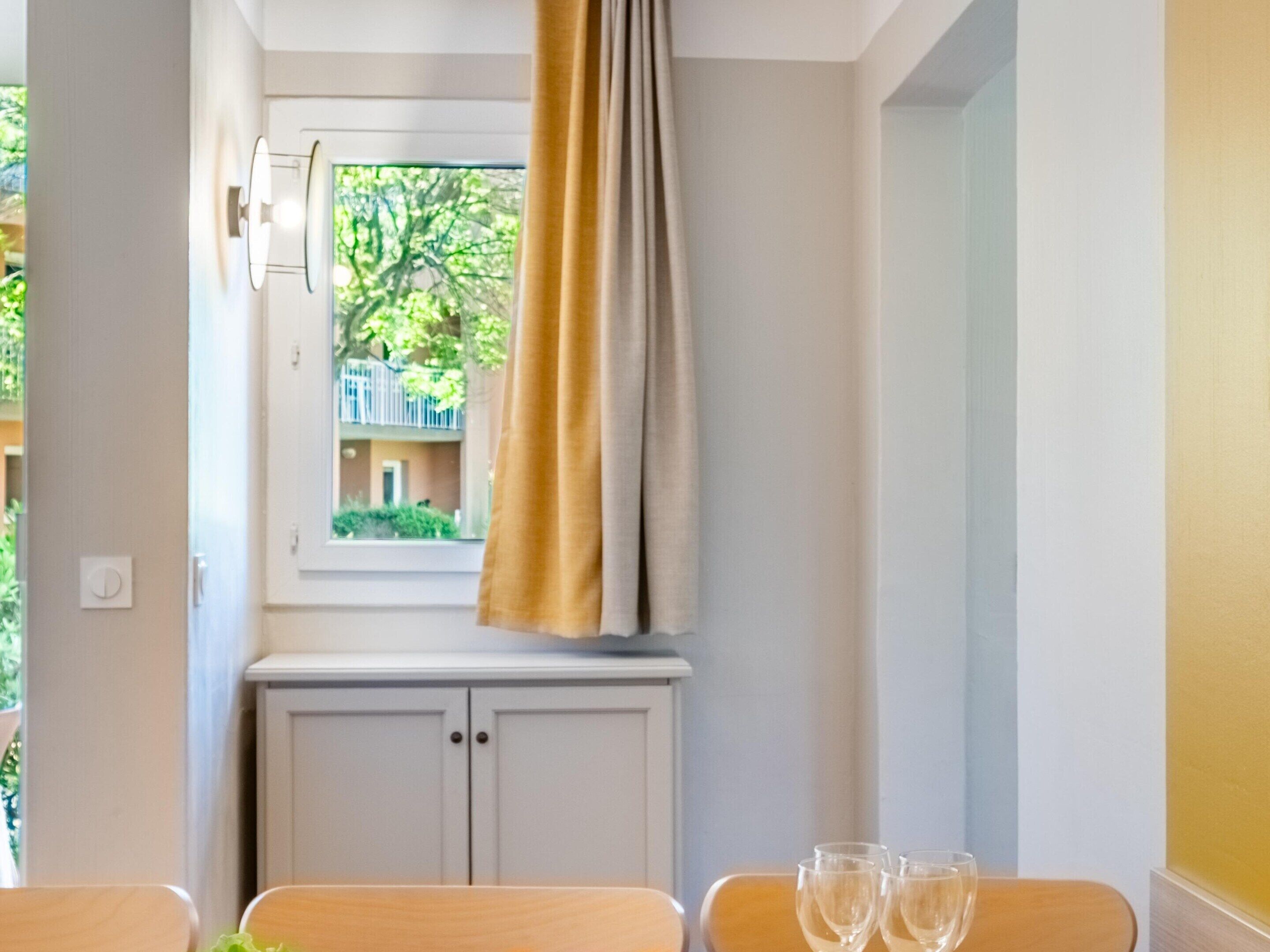 A room with a window, a table with chairs, and a cabinet.
