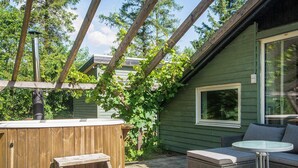 En træterrasse med jacuzzi, udendørs møbler og en pergola.