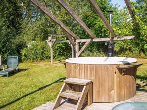 A hot tub with a wooden bench and a step, surrounded by a wooden pergola and greenery. - 5 Star Holiday Home in Bording (Bording)