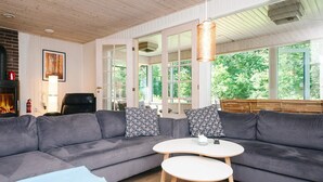 En moderne stue med en grå hjørnesofa, et lille rundt bord og en pejs.