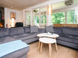Ein modernes Wohnzimmer mit einem grauen Ecksofa, einem kleinen runden Tisch und einem Kamin.