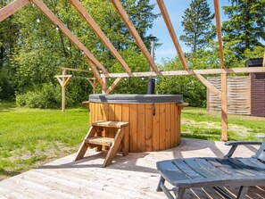 Eine Holztonne mit einer Leiter, einer Holzterrasse und einem Metallstuhl.