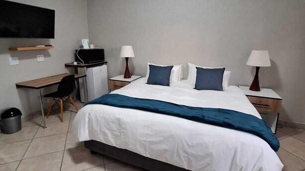 Een hotelkamer met een bed, een bureau, een stoel, een televisie en twee bedlampjes.