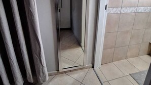 Een kamer met een schuifdeur, betegelde vloer en een gedeeltelijk zicht op een gordijn.
