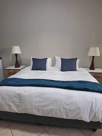 A hotel room with a bed, two bedside tables, and two lamps.. Rams Blissful Guest House