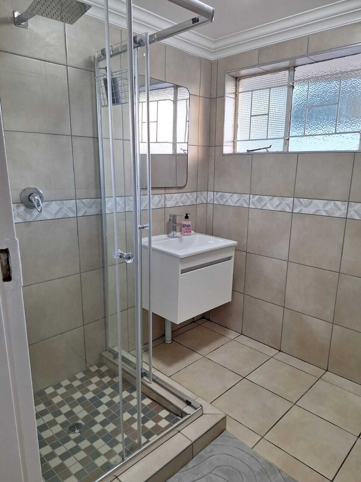 Un bagno con doccia, lavandino e finestra.