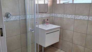 Un bagno con doccia, lavandino e finestra.