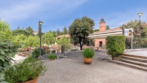 A courtyard with a large planter, a building with a clock tower, and a sign indicating reception. - Spacious Duplex Retreat for 8 (Grospierres)