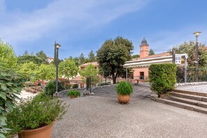 A courtyard with a large planter, a building with a clock tower, and a sign indicating reception. - Spacious Duplex Retreat for 8 (Grospierres)