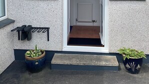A house with a white exterior, a front door, two windows, a small porch, and two potted plants. - Luxury annex, close to Newquay beaches, town, and amenities! Peaceful spot! (Newquay)