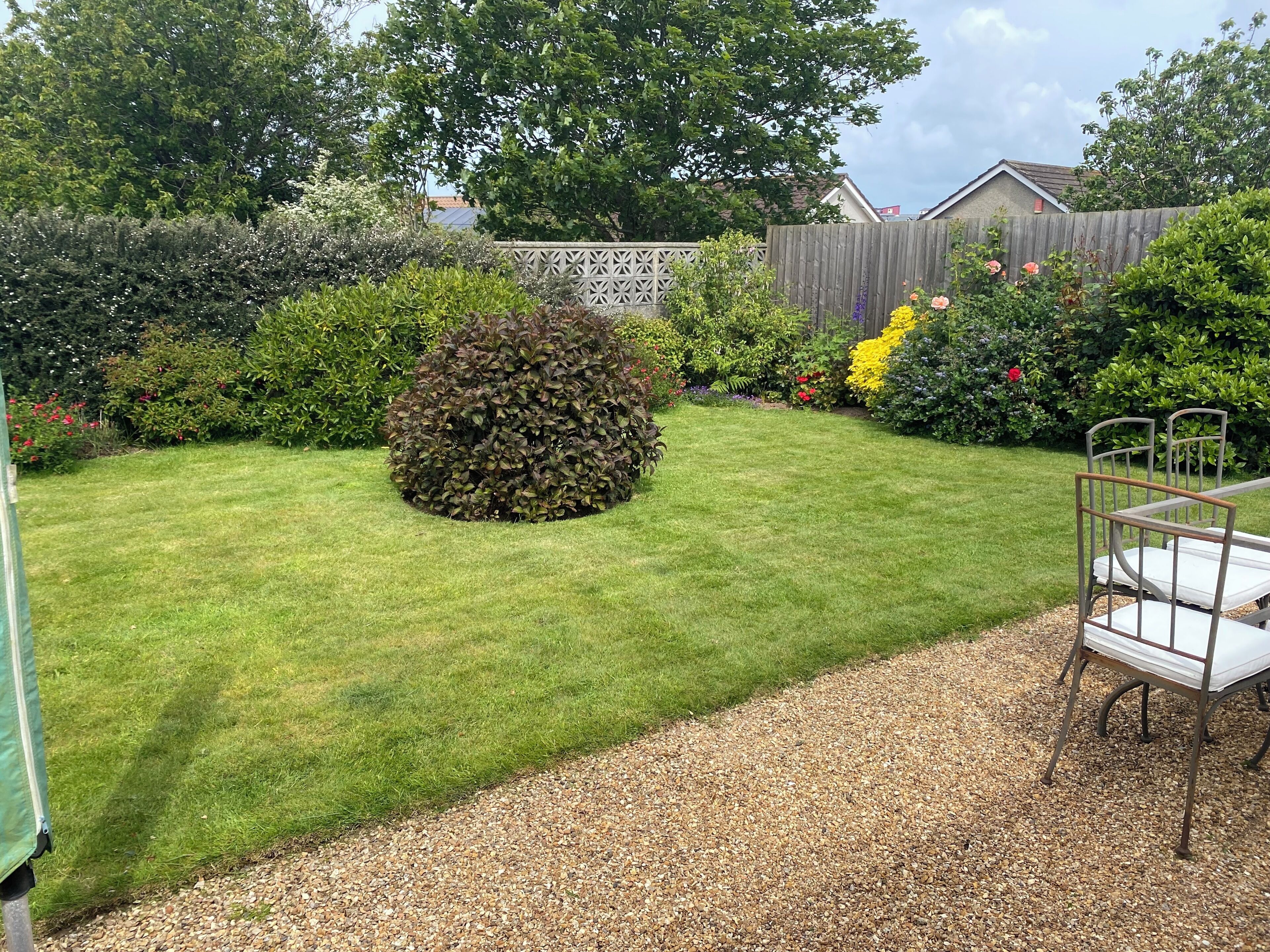 A well-maintained garden with a lawn, a gravel path, and a metal bench.