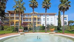 A hotel with a pool, palm trees, and a clear sky. - Apartment with pool and garden in Saint Aygulf (Fréjus)